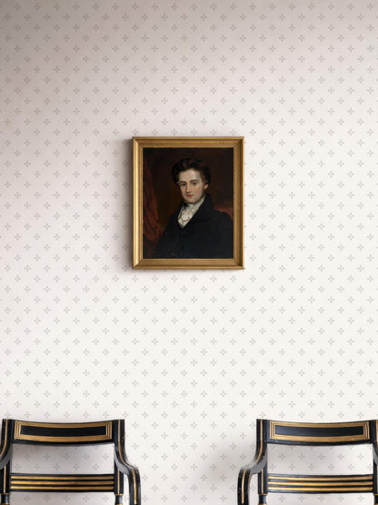 a portrait of a man hanging on a wall, with two black chairs positioned below it.