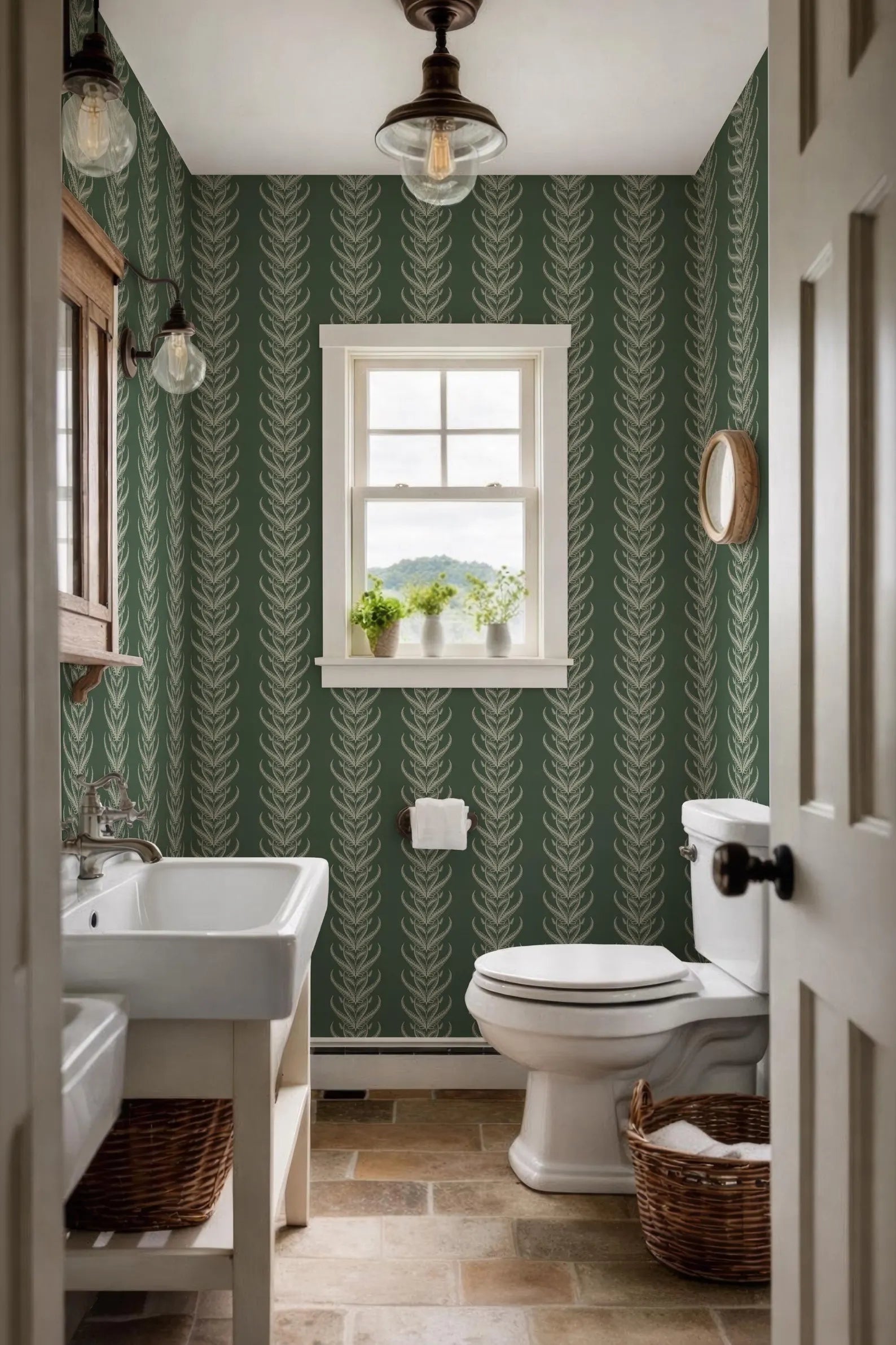 a small bathroom with a white sink, toilet, and a window with a view of the outdoors. The walls are covered in a green and white patterned wallpaper, and the floor is made of tiles. There is a basket on the floor next to the toilet.