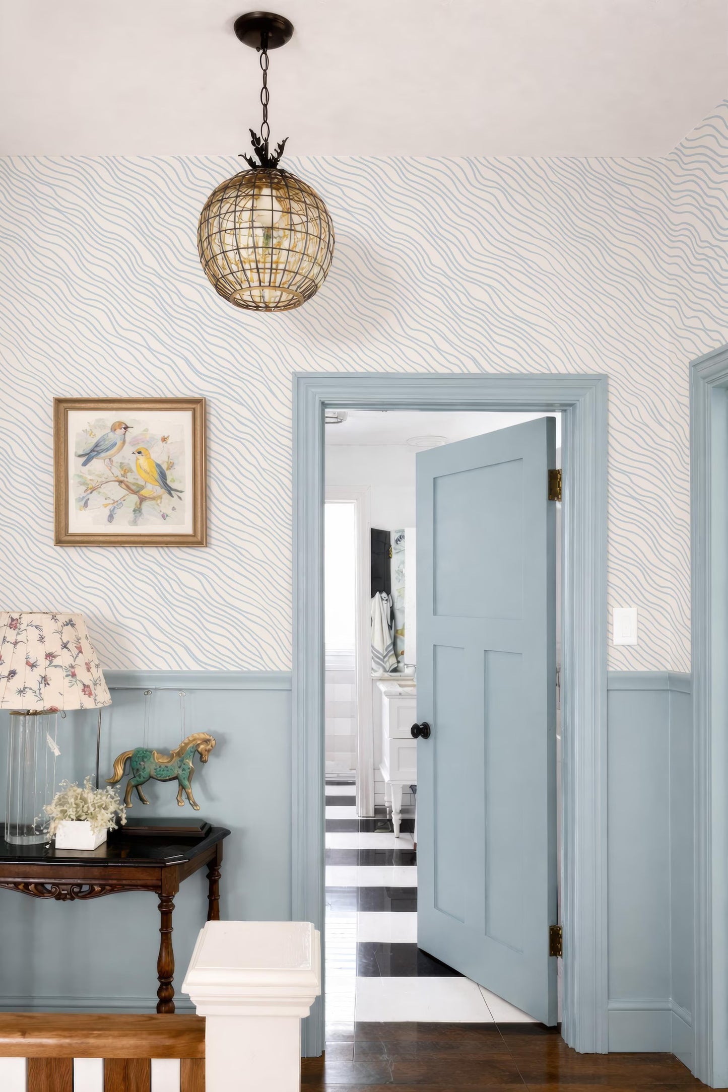 a cozy and inviting entryway with a light blue door, a chandelier, and a painting on the wall. The room has a checkered floor and a wooden bench, creating a warm and welcoming atmosphere.