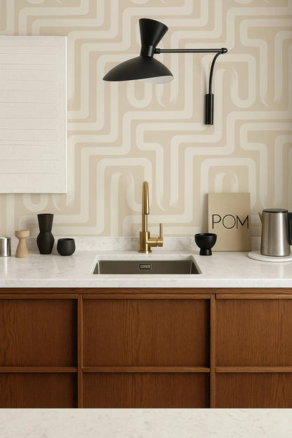 a modern kitchen with a wooden cabinet, a sink, and a black lamp. The walls are adorned with a geometric pattern wallpaper, and there are various decorative items on the countertop, including a bowl, a vase, and a coffee maker.