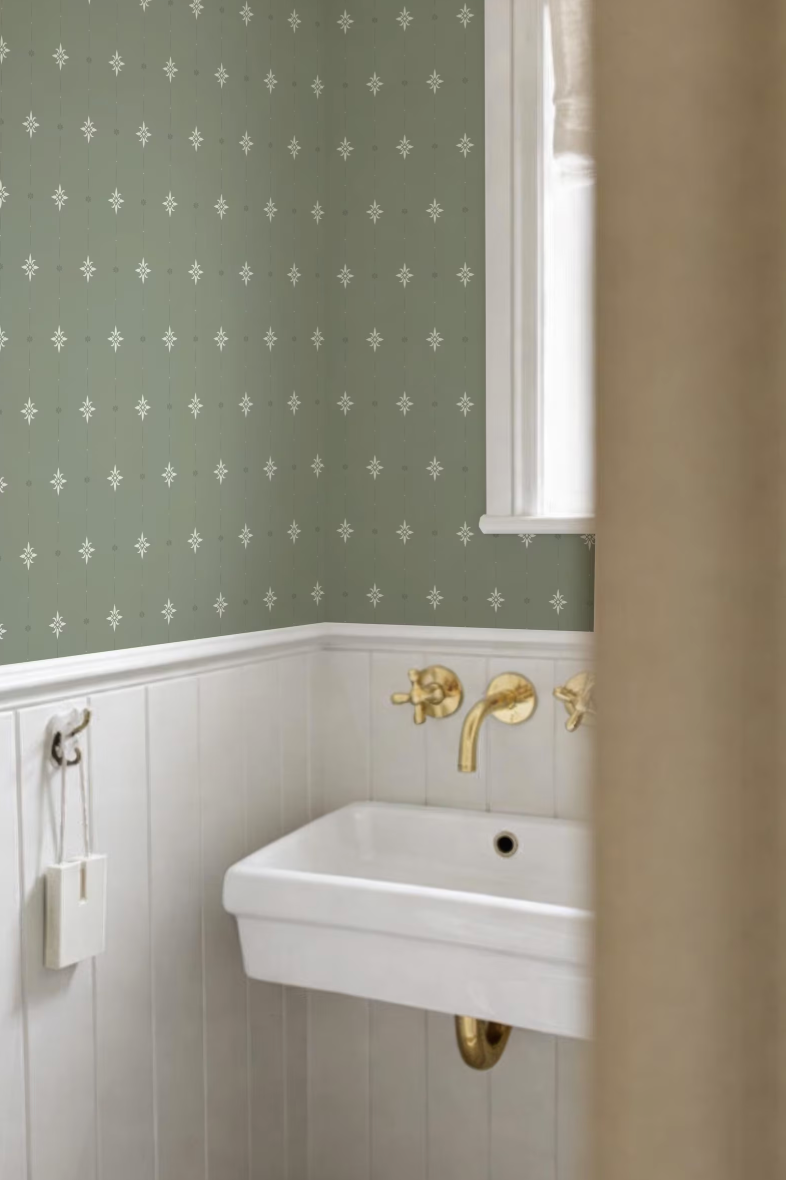 a bathroom with a white sink and a green patterned wallpaper.