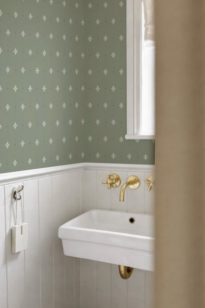 a bathroom with a white sink and a green patterned wallpaper.