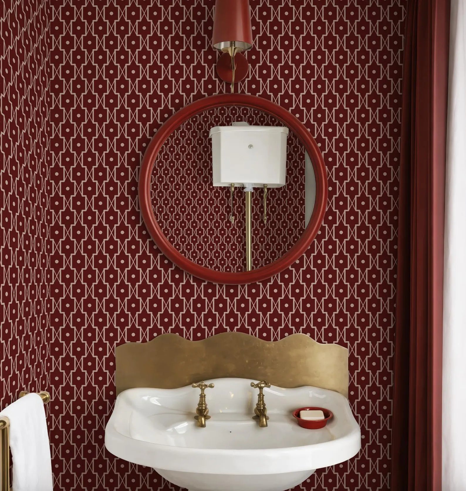 a bathroom with a white sink, a red circular mirror, and a red curtain. The walls are covered in a red and white patterned wallpaper.