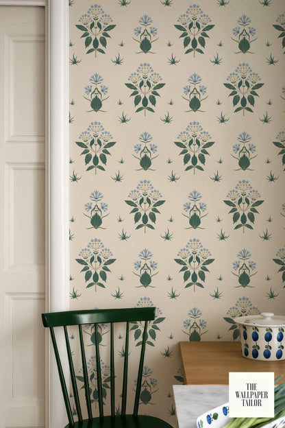 a wallpapered wall with a repeating pattern of green and white floral designs, including pears and leaves. A green chair is positioned in front of the wall, and a small white bowl is visible on a surface nearby.
