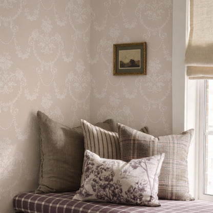 a cozy corner of a room with a window, featuring a bed with decorative pillows and a framed picture on the wall.
