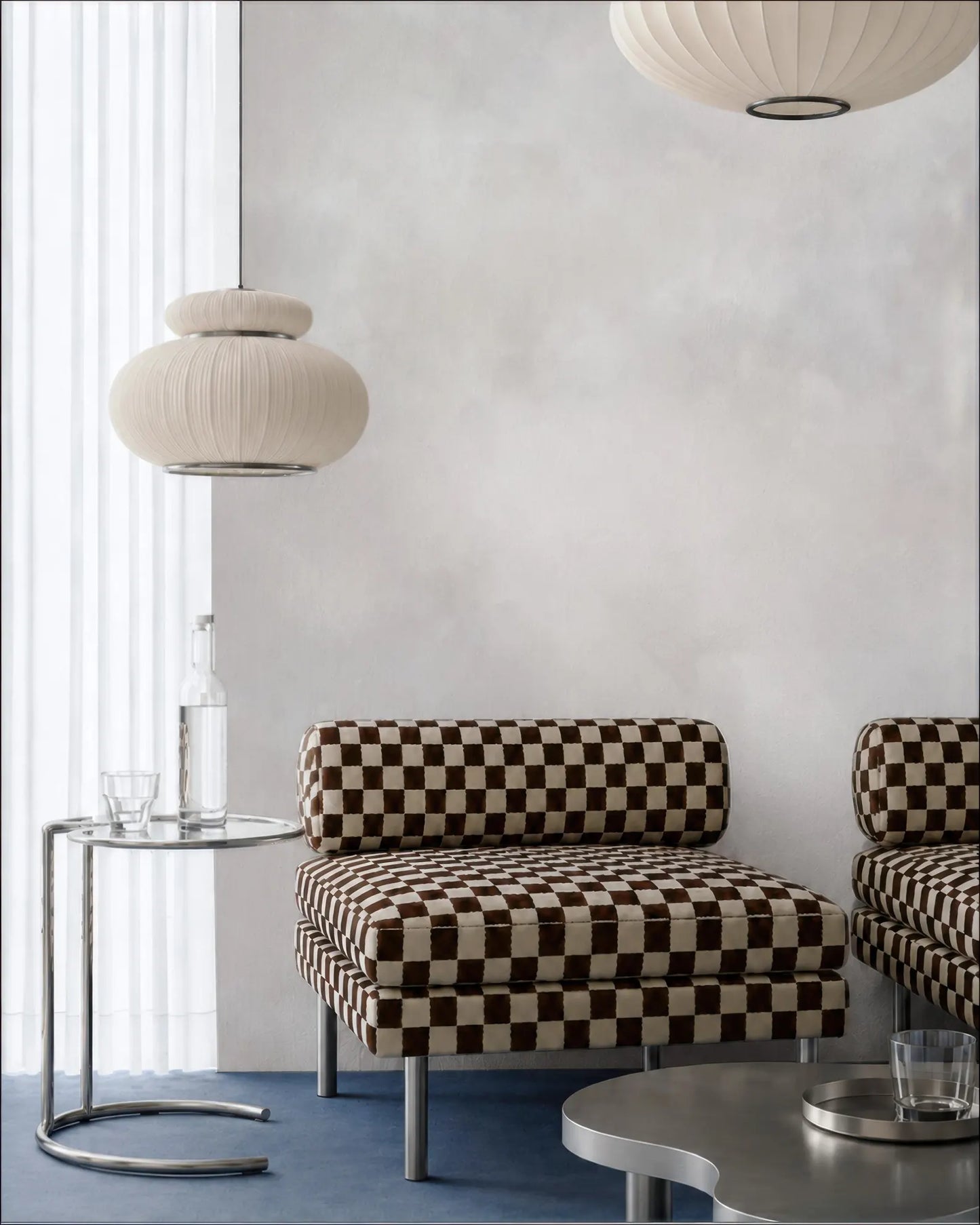 a modern living room with a checkered patterned sofa, a round table with a glass top, and two pendant lights hanging above the sofa.