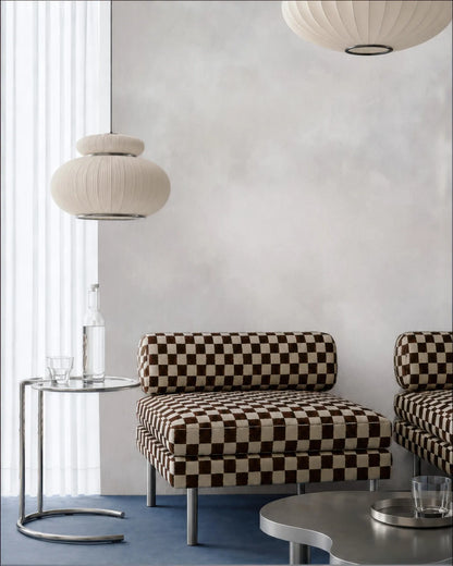 a modern living room with a checkered patterned sofa, a round table with a glass top, and two pendant lights hanging above the sofa.