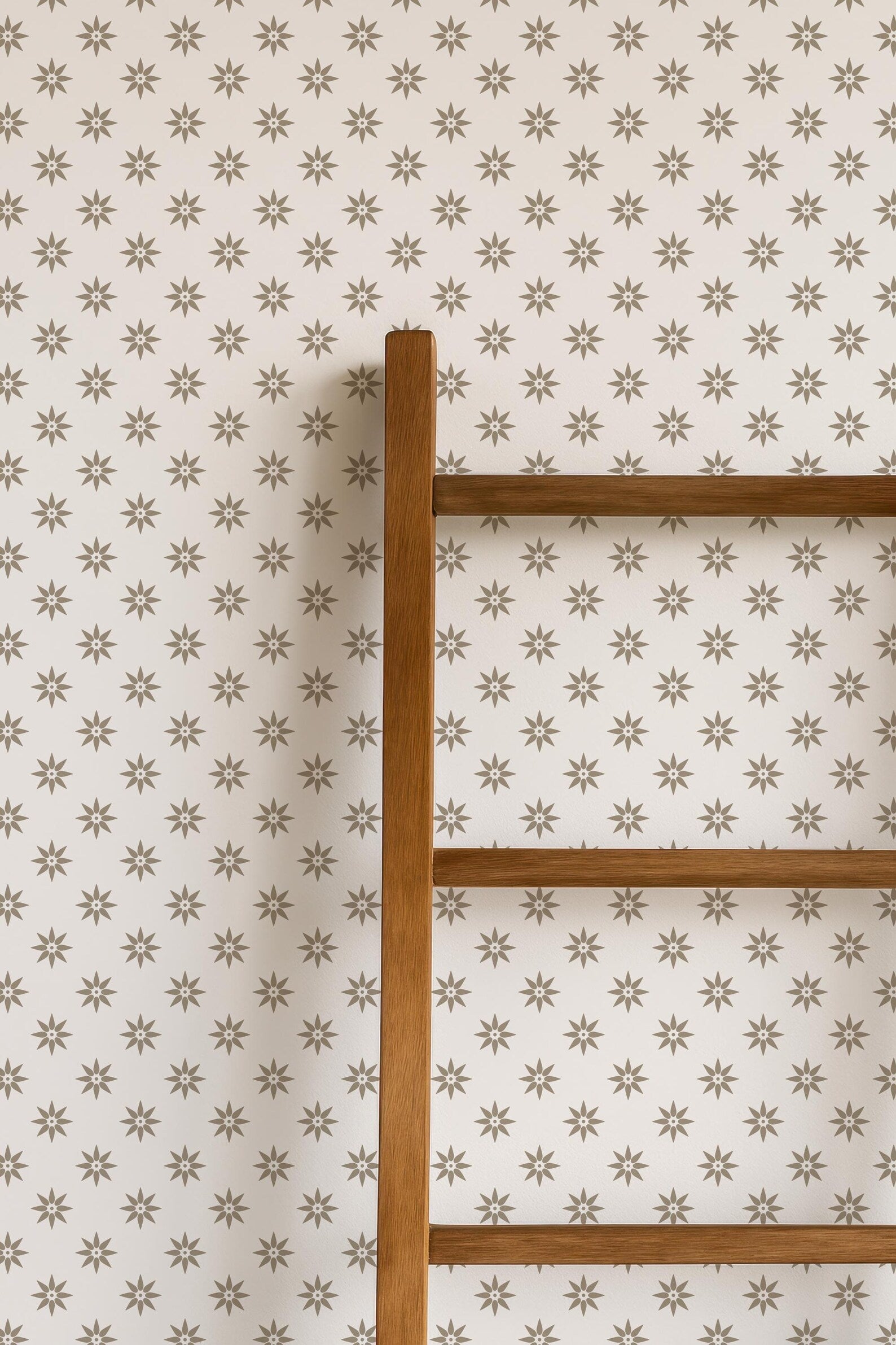 a wooden ladder against a wall with a repeating star pattern.