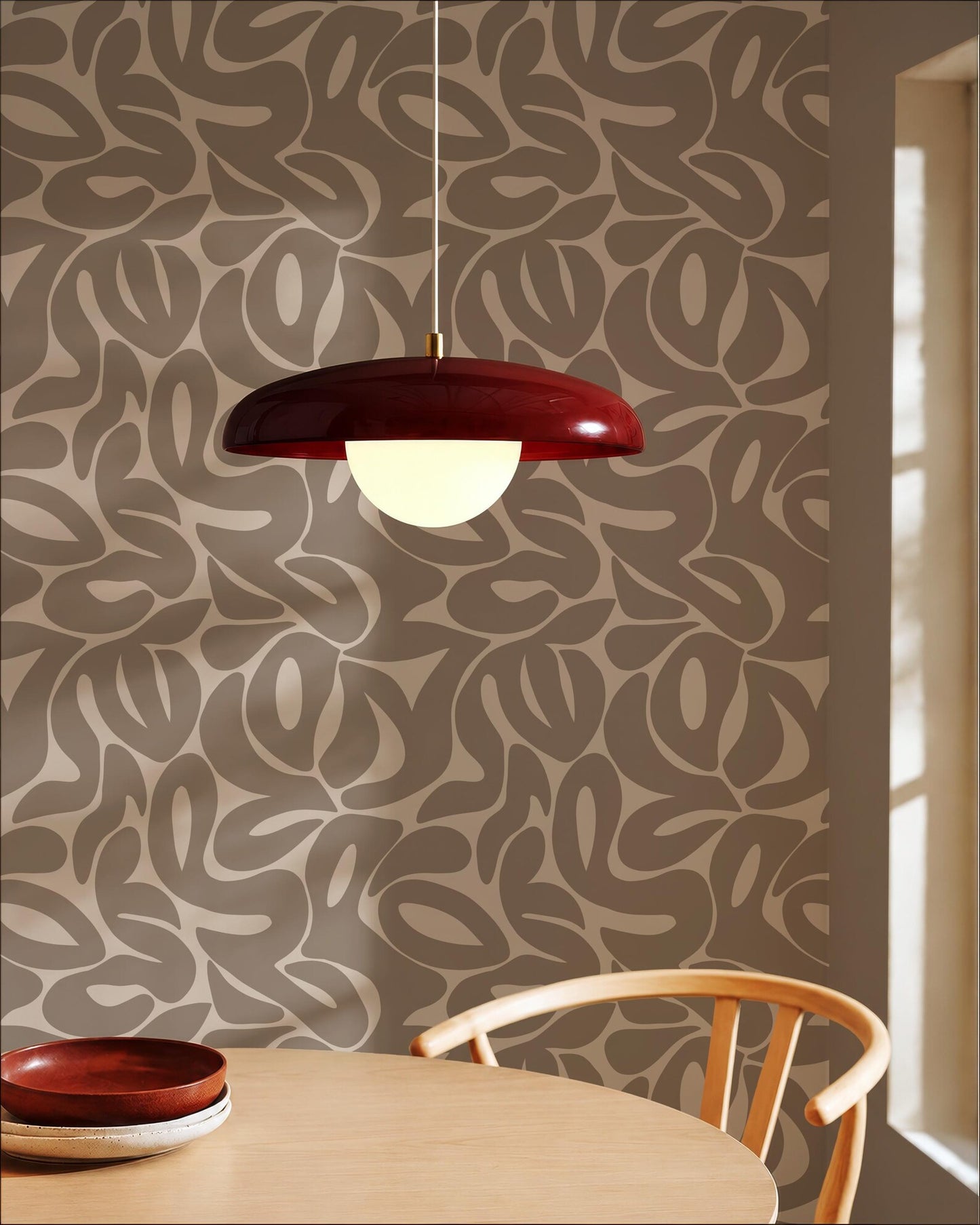 a modern dining room with a wooden table and chair, a red pendant light hanging above the table, and a patterned wall behind the table.