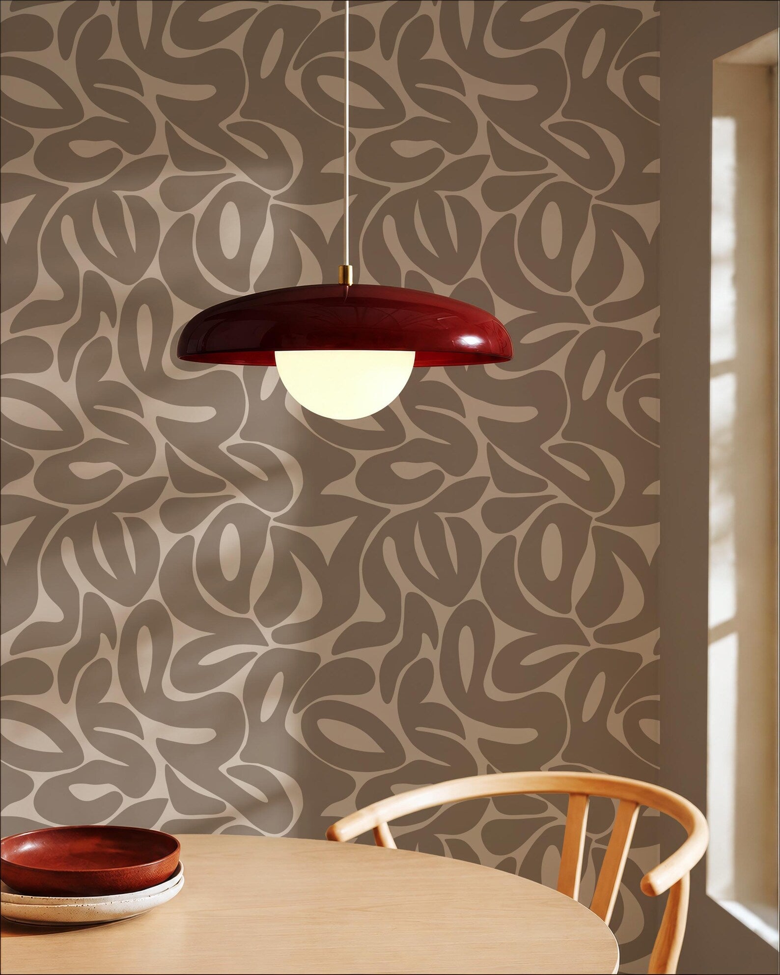 a modern dining room with a wooden table and chair, a red pendant light hanging above the table, and a patterned wall behind the table.