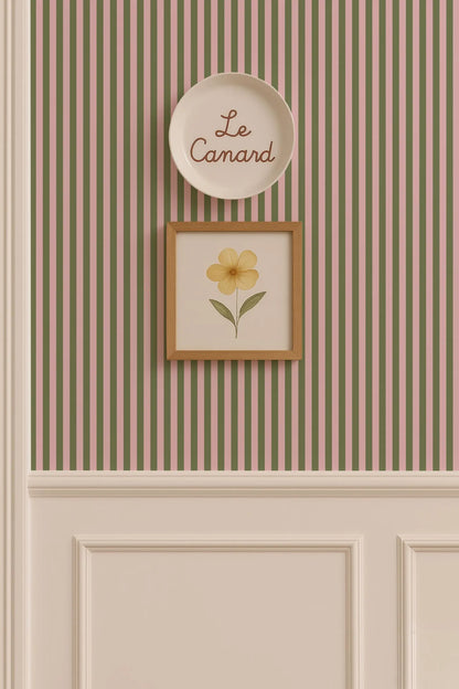 a wall with a framed picture of a yellow flower and a plate with the word "Le Camand" written on it.