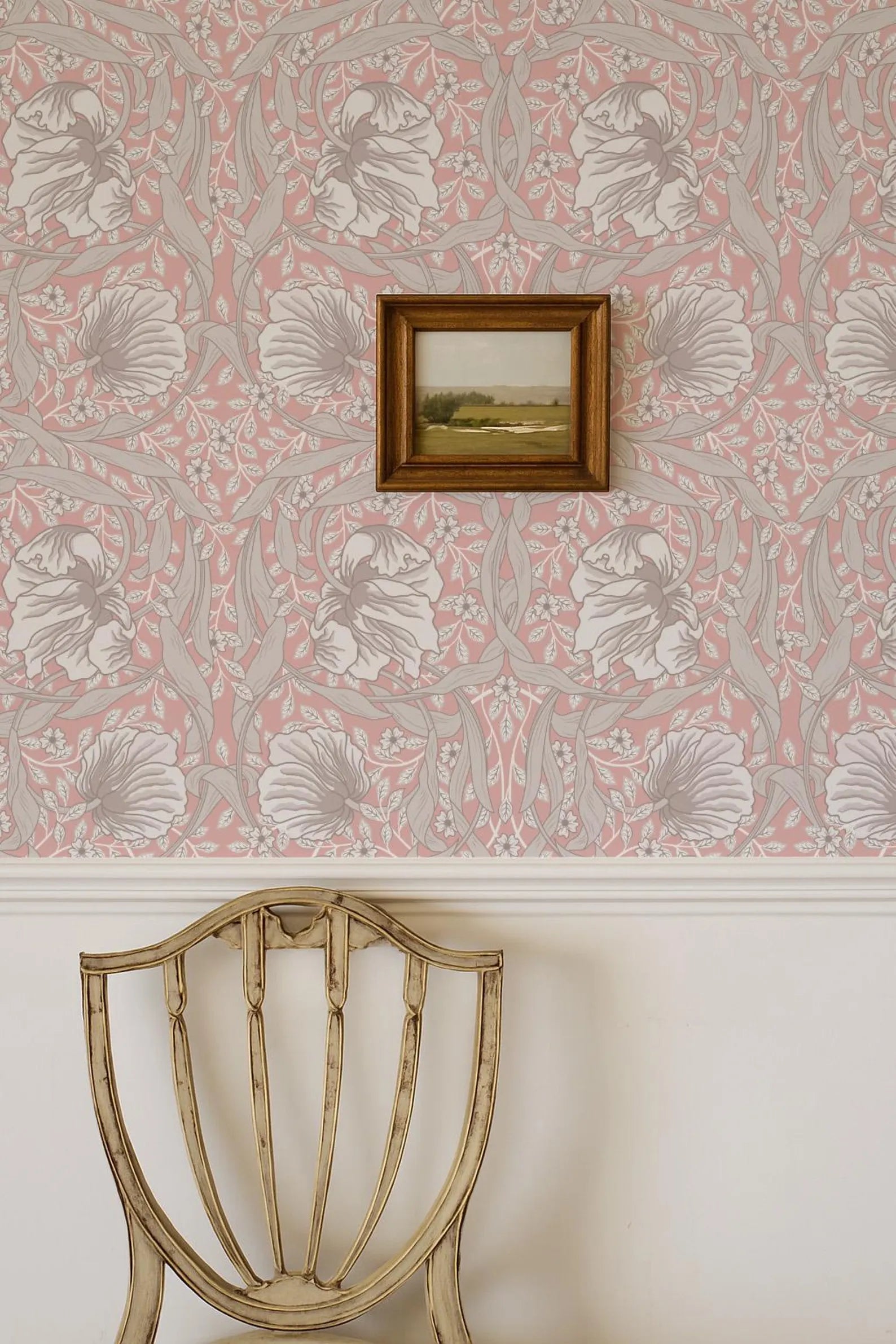 a wooden chair with a floral patterned wall behind it, and a framed landscape painting hanging on the wall.