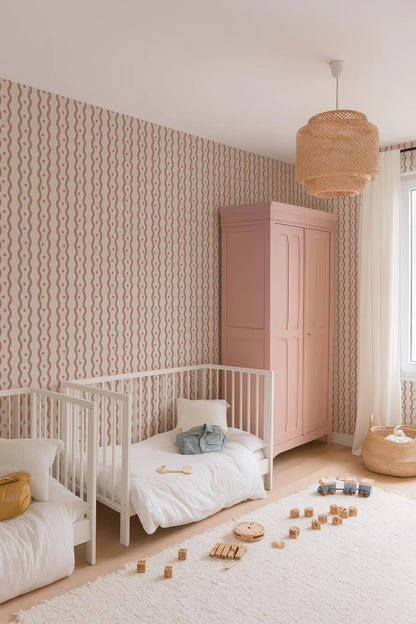 a cozy and well-organized nursery room with two white cribs, a pink armoire, and a hanging light fixture. The room is decorated with a patterned wallpaper and has a white rug on the floor. There are also some wooden blocks scattered on the floor, suggesting a playful and creative atmosphere.