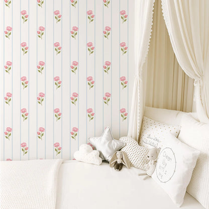 a cozy and inviting bedroom scene, featuring a bed with white linens and a canopy, a wallpapered wall with a repeating pattern of pink flowers, and a collection of stuffed animals and decorative pillows on the bed.