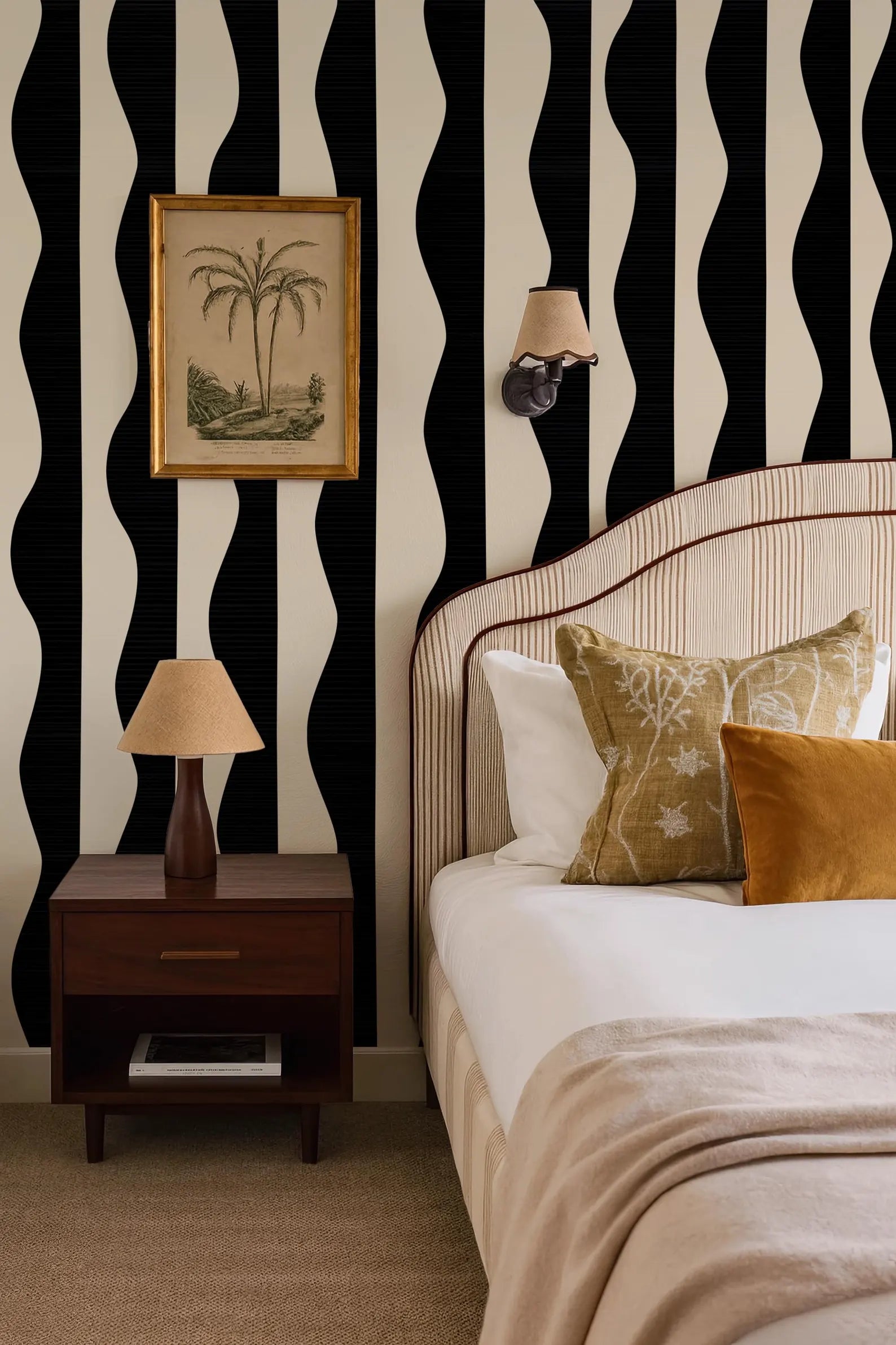 a bedroom with a bed, a nightstand, and a framed picture on the wall. The room has a black and white striped wallpaper, and the bed is adorned with a white comforter and a gold throw pillow.
