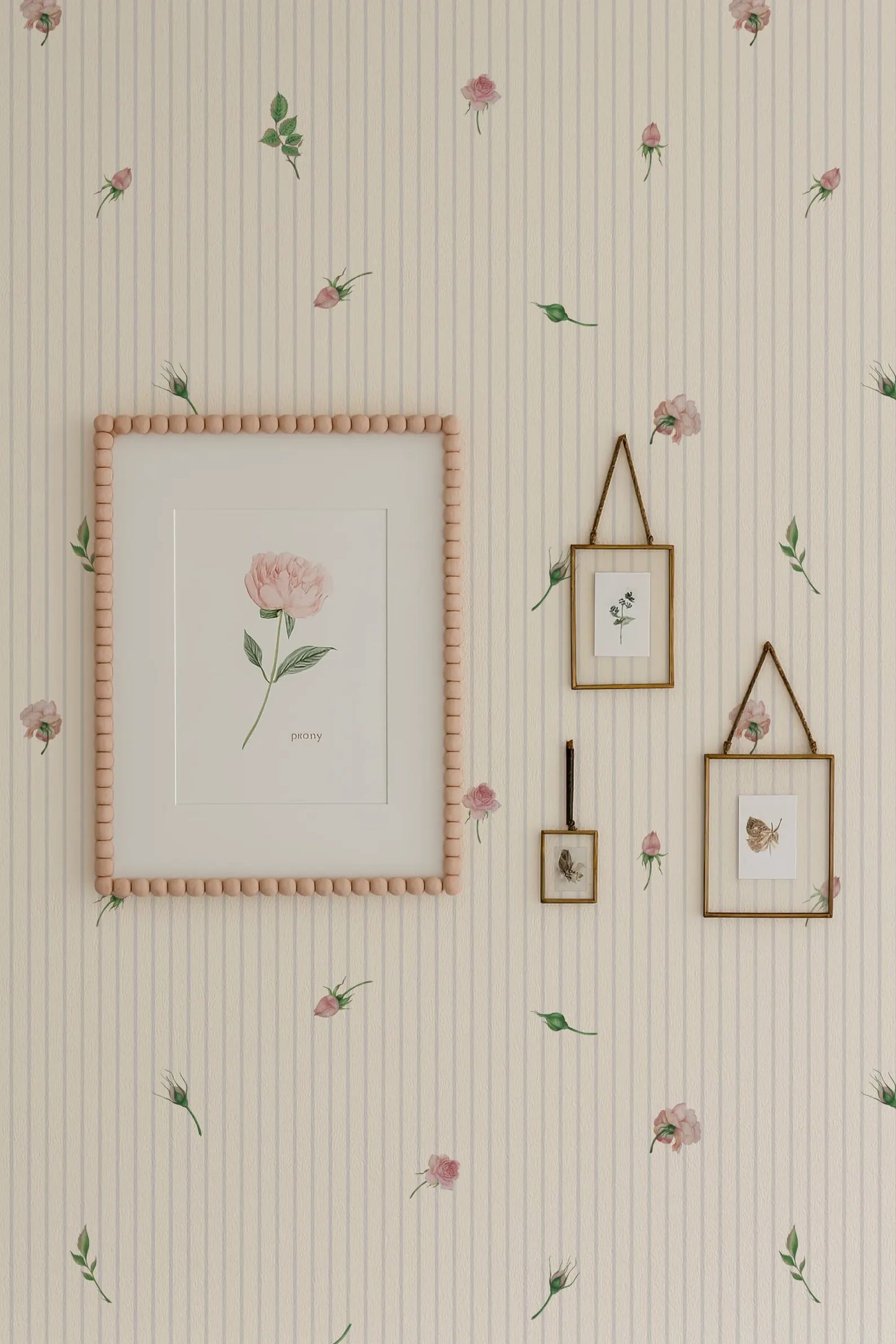 a wallpapered wall with a framed picture, two framed pictures, and a framed picture hanging on it. The wallpapered wall has a floral pattern, and the framed pictures and picture frame are also adorned with a floral pattern.
