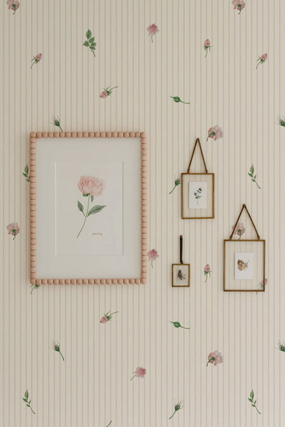 a wallpapered wall with a framed picture, two framed pictures, and a framed picture hanging on it. The wallpapered wall has a floral pattern, and the framed pictures and picture frame are also adorned with a floral pattern.
