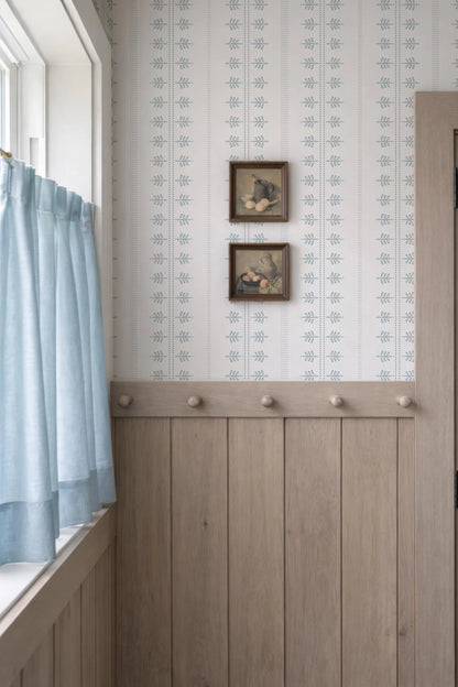 a cozy corner with a wooden wall, a window with blue curtains, and two framed pictures hanging on the wall.