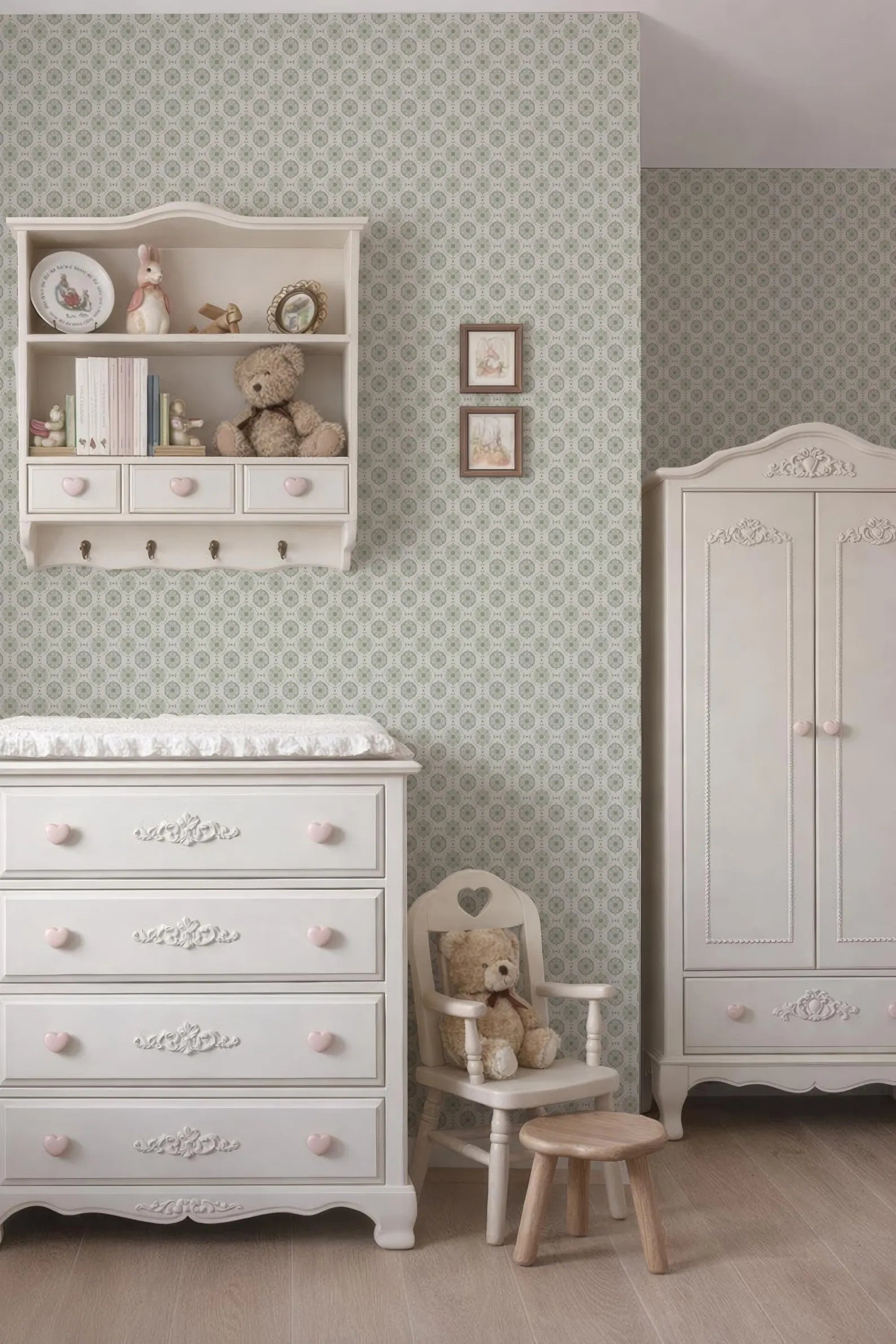 a cozy and charming nursery room with a white dresser, a white chair, and a white cabinet. The room has a patterned wallpaper and a teddy bear on the dresser.