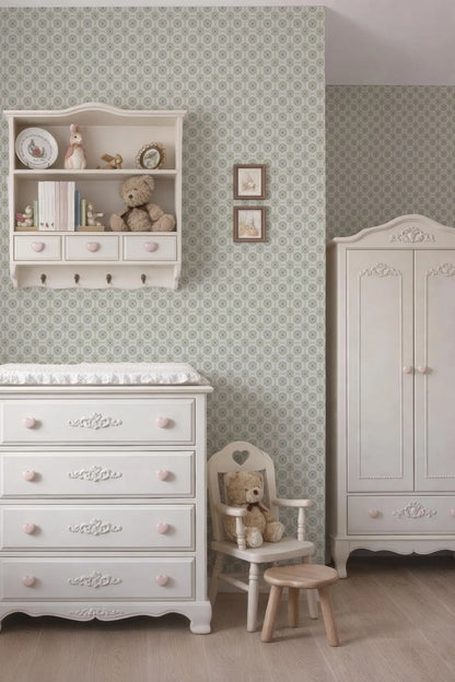 a cozy and charming nursery room with a white dresser, a white chair, and a white cabinet. The room has a patterned wallpaper and a teddy bear on the dresser.