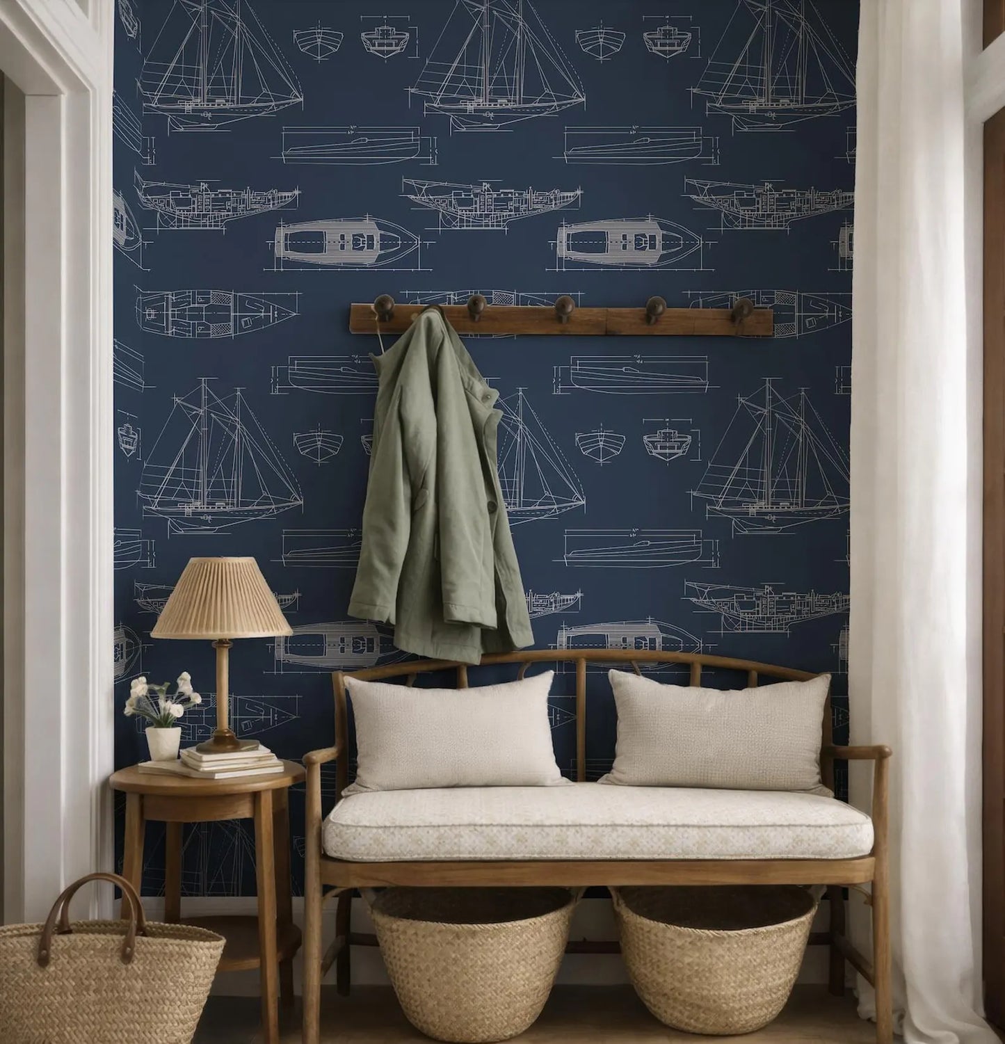 a cozy nautical-themed room with a blue wall adorned with white illustrations of boats and ships. A wooden bench with two white cushions is positioned in front of the wall, and a coat rack is mounted above it. A small table with a lamp and a book is also present in the room.