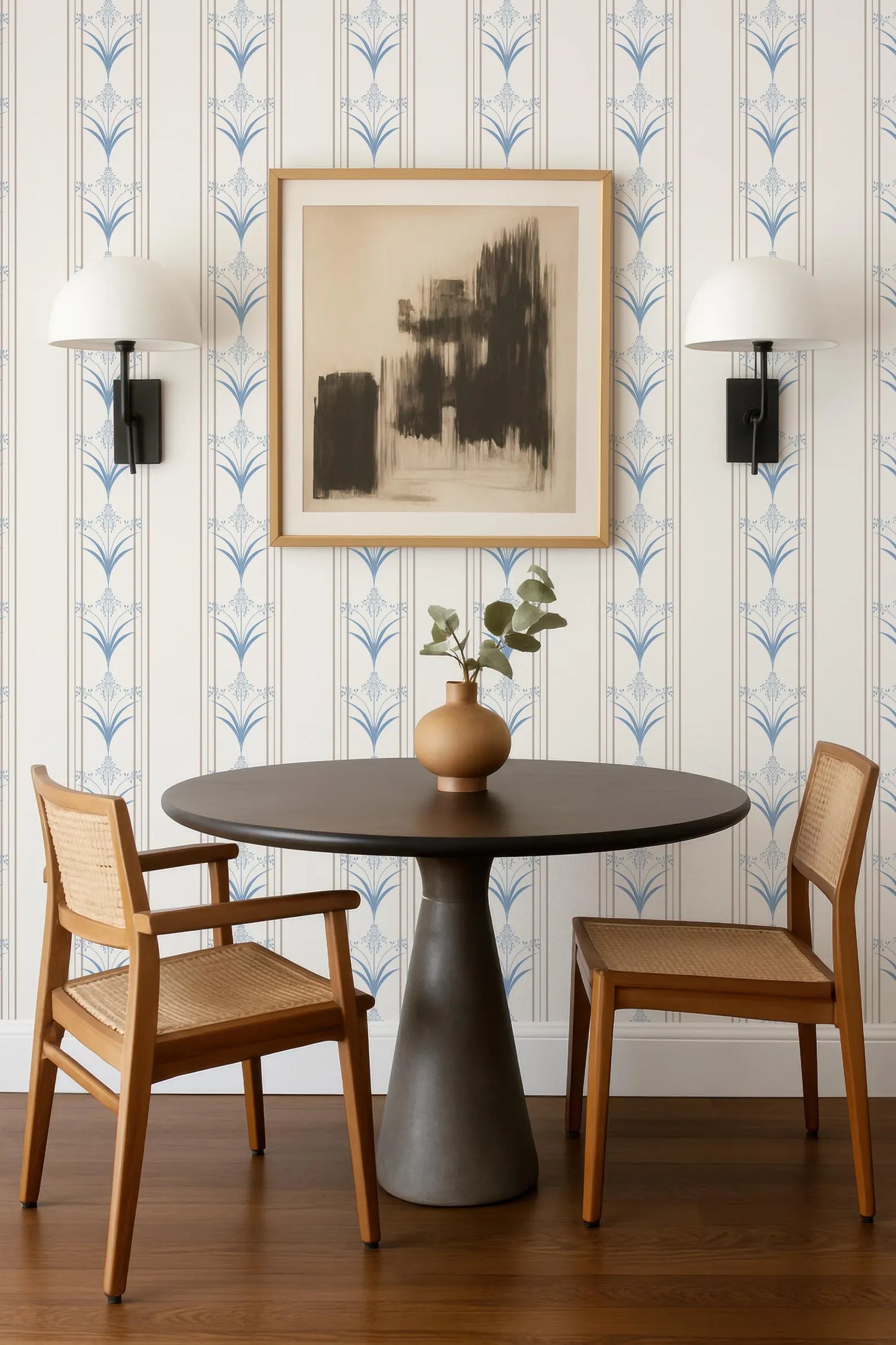 a modern dining area with a round wooden table, two wooden chairs, and a framed abstract artwork on the wall above the table.