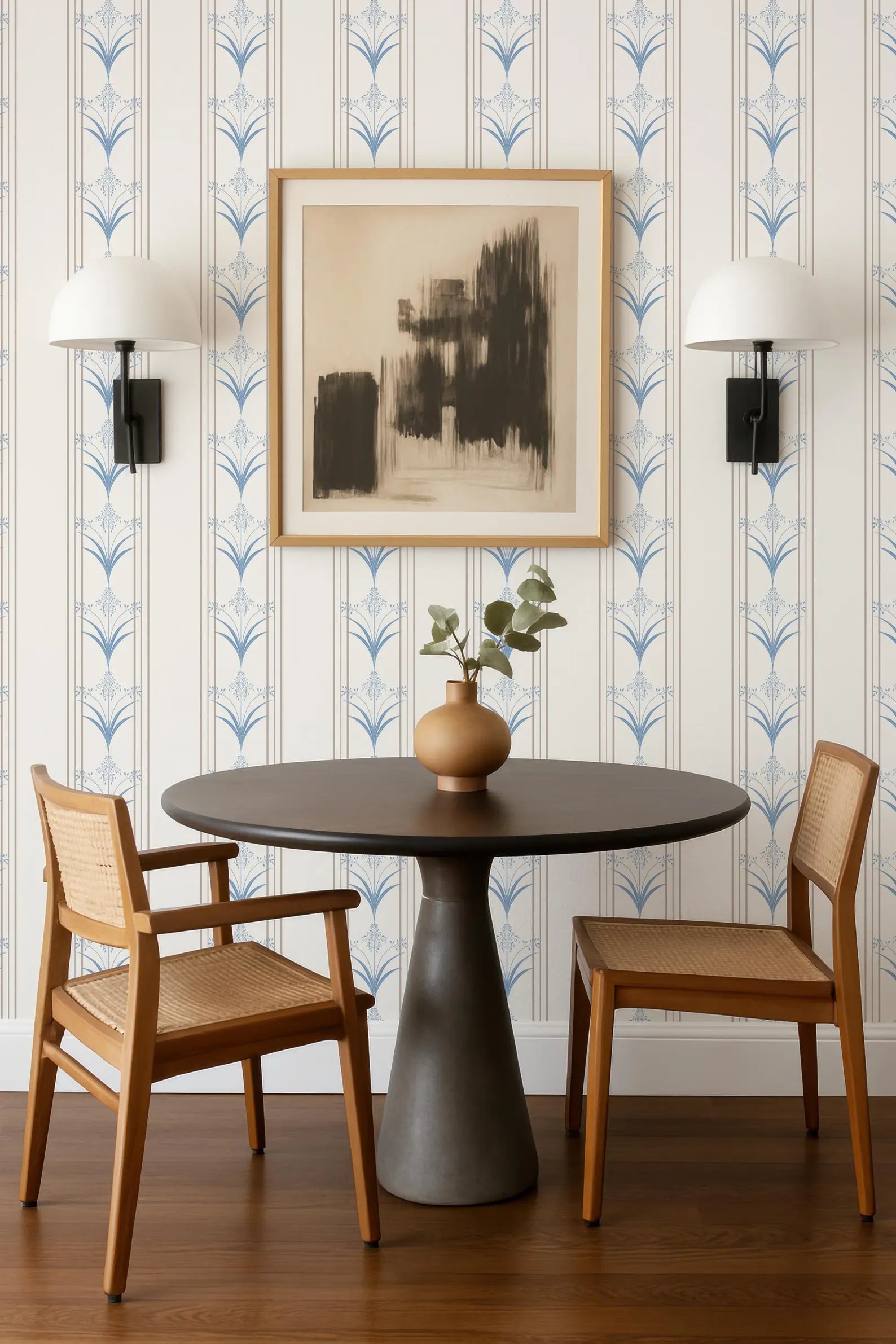 a modern dining area with a round wooden table, two wooden chairs, and a framed abstract artwork on the wall above the table.